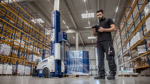 Imagefilm Industriefotografie für Nelo Neuss Logistik, die einen Lagerist in Arbeitskleidung im modernen Lager mit Packroboter zeigt